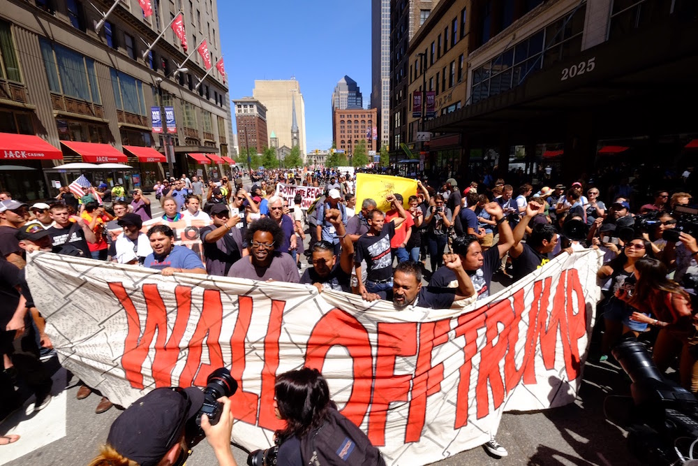 Activists marching with Wall Off Trump Banner