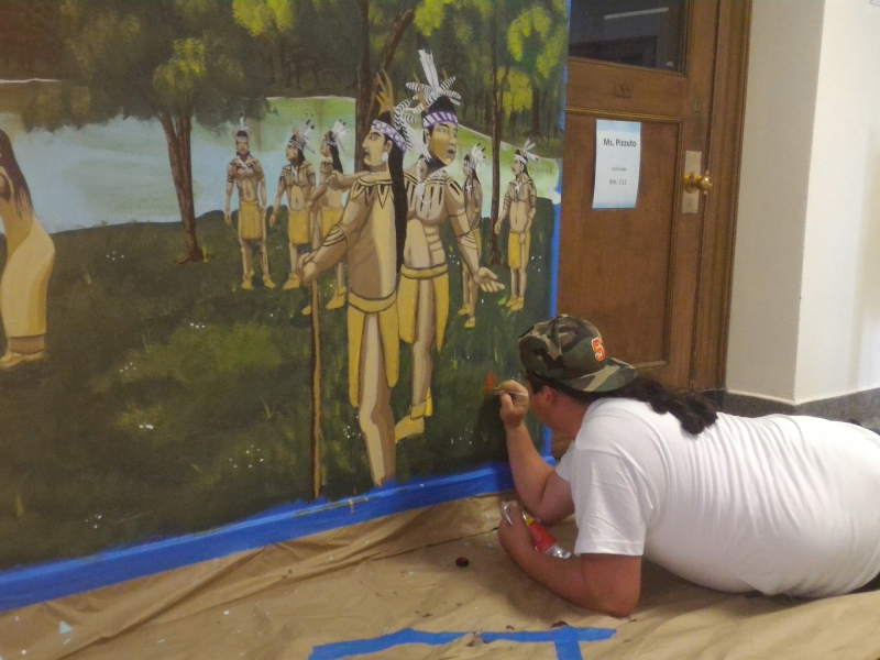 Brandon Lazore signing the new Great Law of Peace mural at LeMoyne Elementary